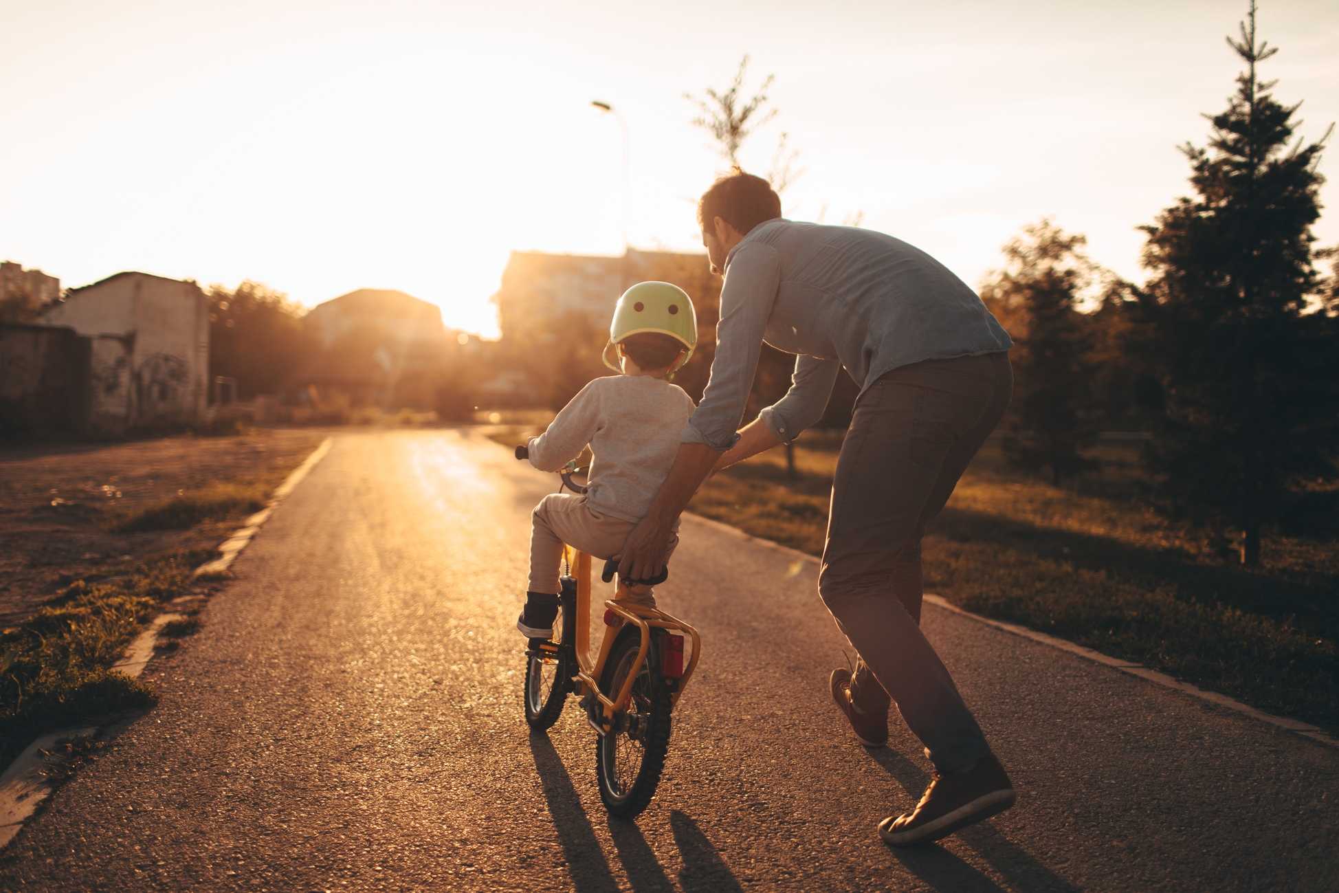 Father coaching his child how to ride a bike.